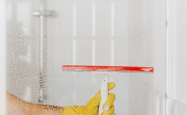 Cleaning a glass shower door at a Rise Co-Host property in Canmore